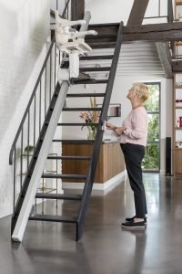 Picture of lady using the remote to bring the stairlift downstairs