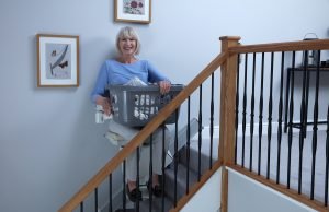 Picture showing a lady using her Handicare 1100 to carry laundry upstairs on her lap