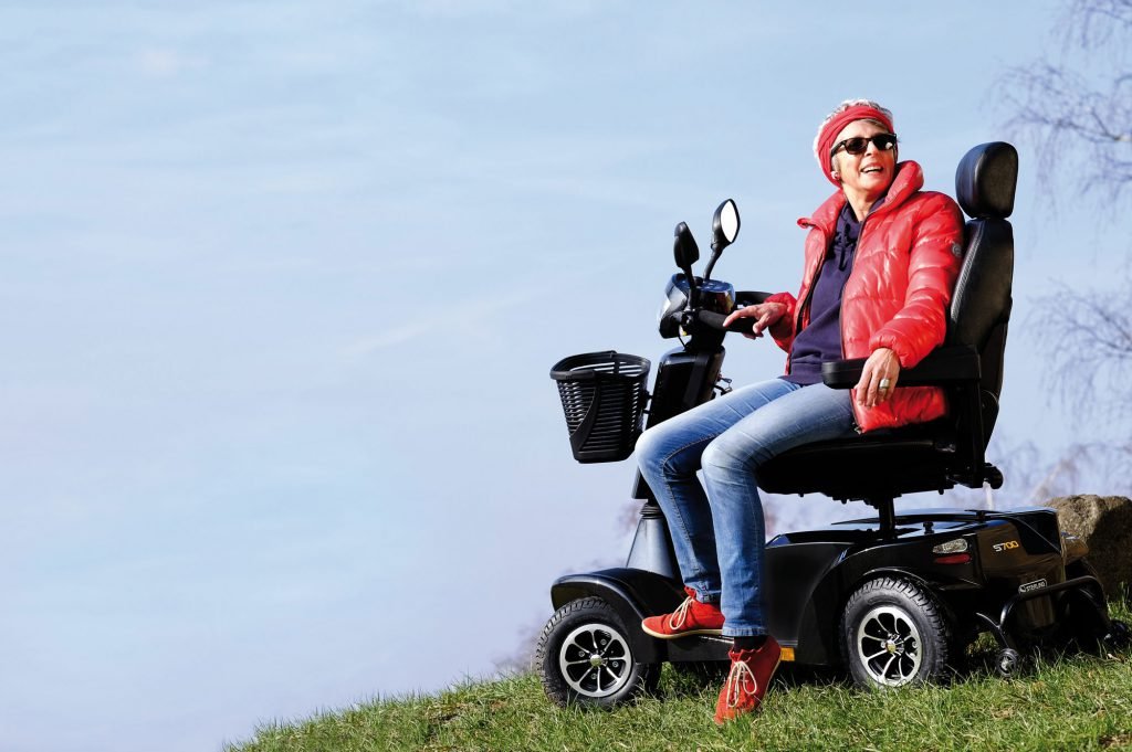Picture of a lady getting off her S700 mobility scooter in the park