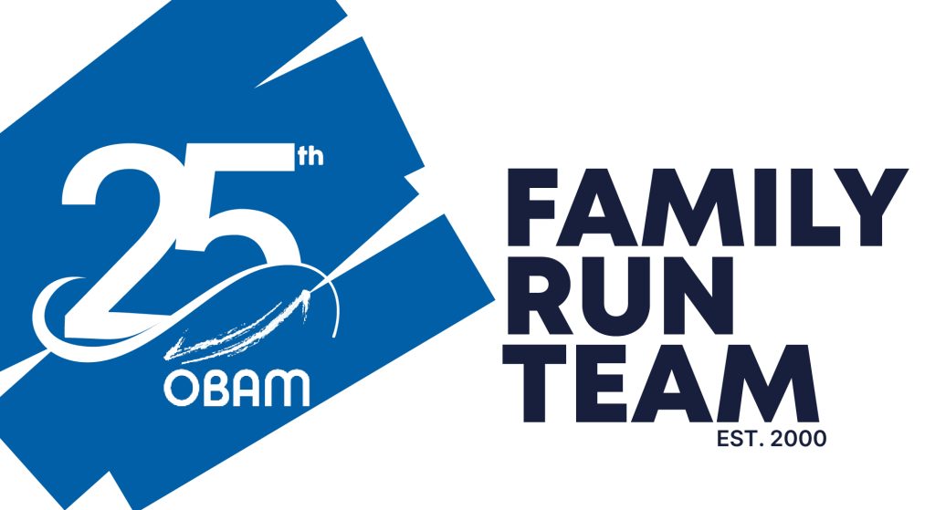 Logo featuring "25th OBAM" on a blue background with the text "FAMILY RUN TEAM EST. 2000" in bold black letters on a white background, celebrating a Boston couple's legacy and their commitment to stairlift donation.