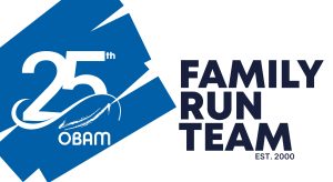 Logo featuring "25th OBAM" on a blue background with the text "FAMILY RUN TEAM EST. 2000" in bold black letters on a white background, celebrating a Boston couple's legacy and their commitment to stairlift donation.
