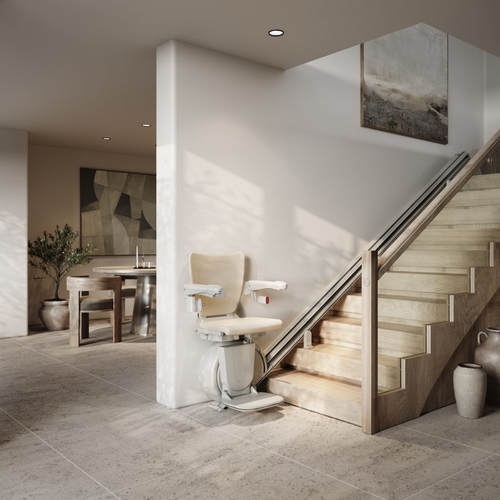 A beige Savaria K2 stairlift is installed along a wooden staircase in a modern, minimalist home with neutral-coloured decor and tiled flooring.