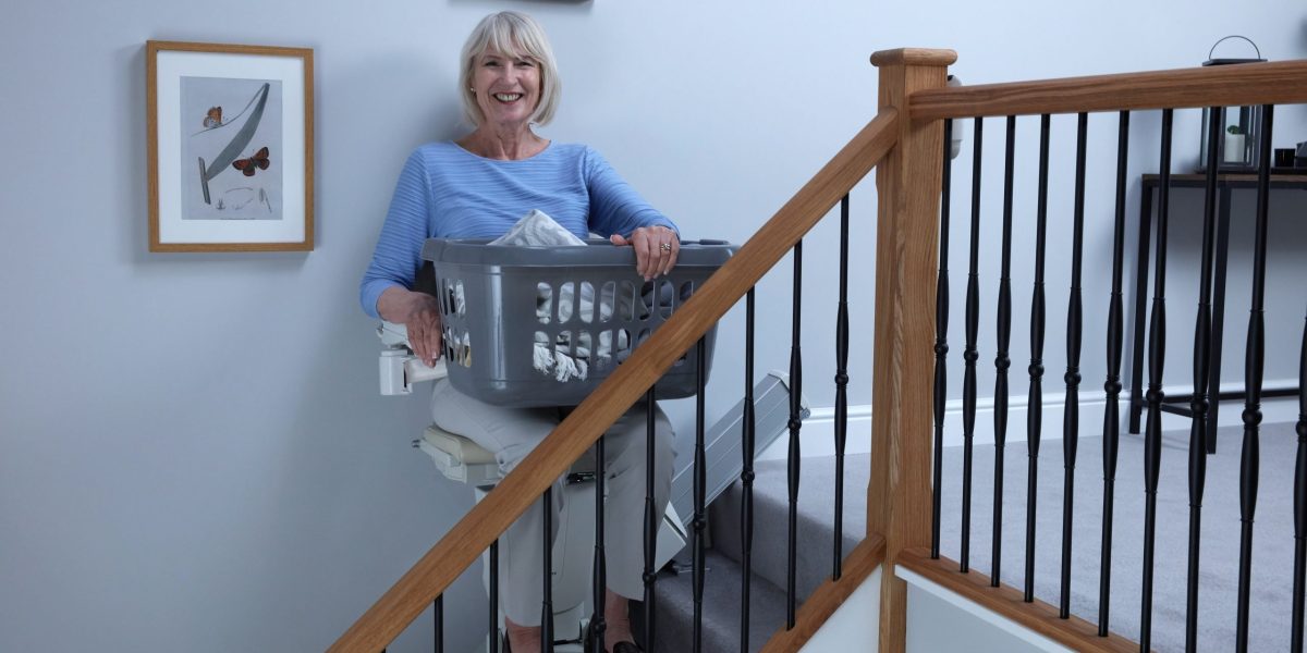 Picture showing lady taking laundry upstairs on her Handicare 1100 stairlift
